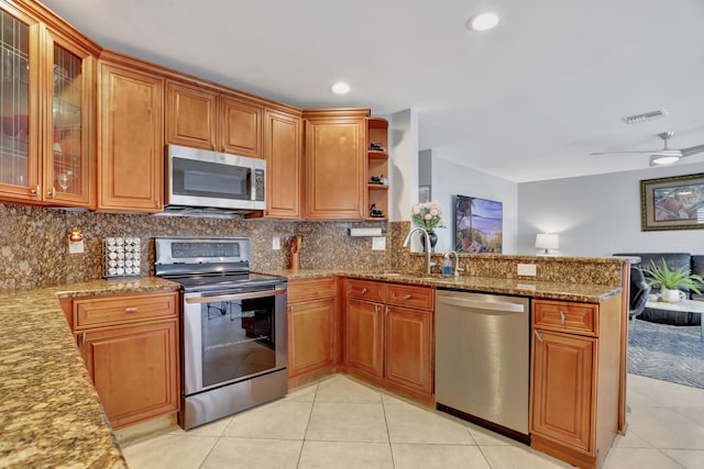 kitchen featuring ceiling fan, sink, kitchen peninsula, appliances with stainless steel finishes, and light stone countertops