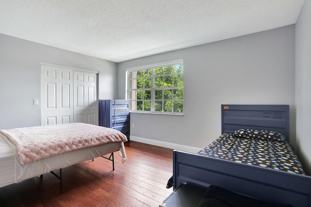 bedroom featuring a textured ceiling, dark hardwood / wood-style flooring, and a closet