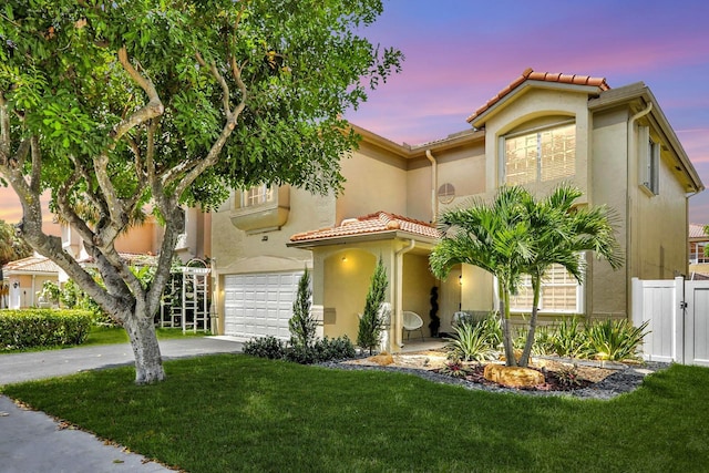 mediterranean / spanish house featuring a garage and a yard