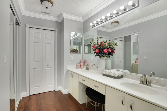 bathroom with a textured ceiling, wood-type flooring, vanity, and ornamental molding