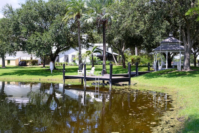 view of dock featuring a water view, a lawn, and a gazebo