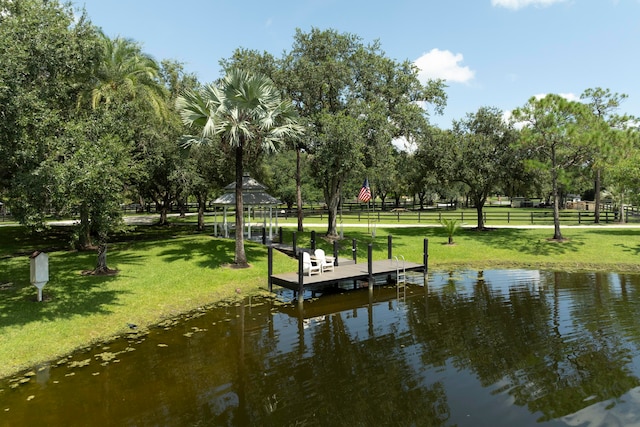 dock area with a water view, a lawn, and a gazebo