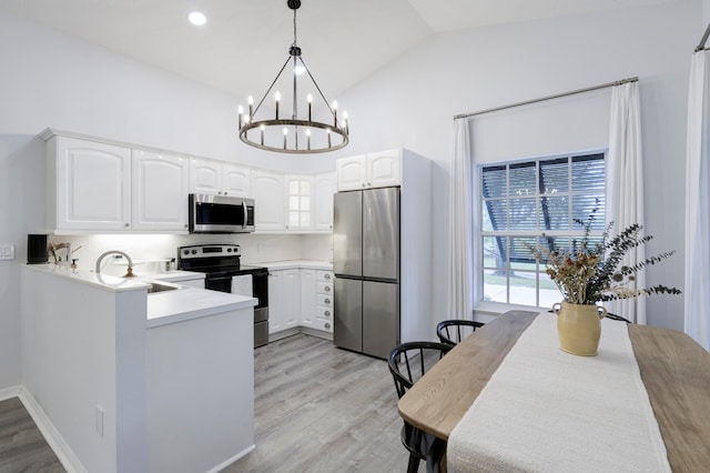 kitchen with an inviting chandelier, white cabinetry, stainless steel appliances, and light hardwood / wood-style floors