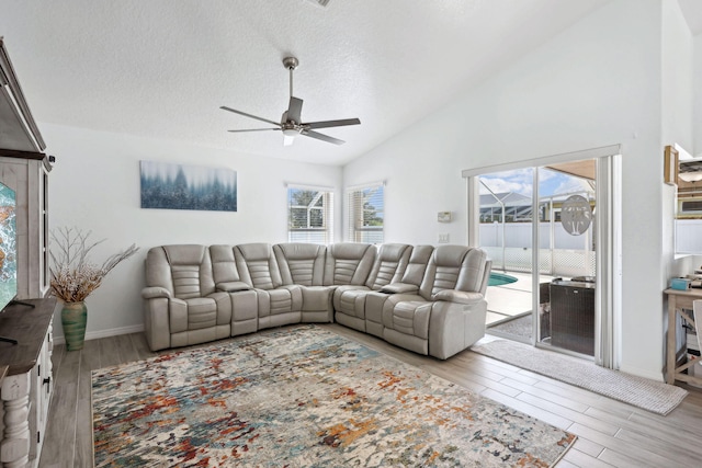 living room featuring ceiling fan, high vaulted ceiling, a textured ceiling, and light hardwood / wood-style flooring