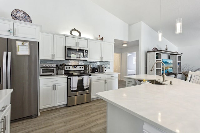 kitchen with sink, stainless steel appliances, decorative backsplash, and white cabinets