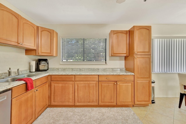 kitchen featuring light stone countertops, light tile patterned floors, dishwasher, and sink