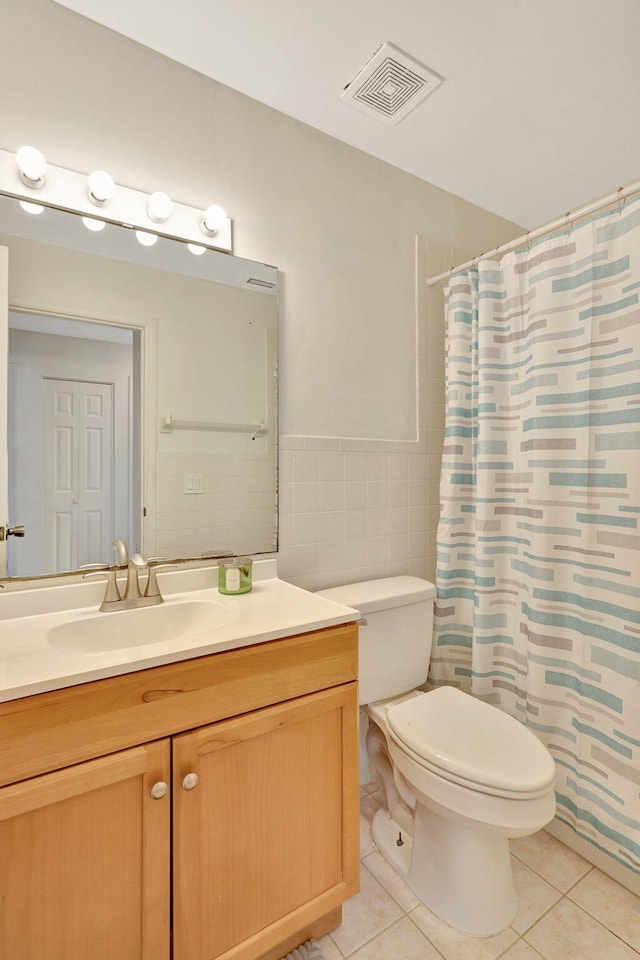 bathroom with toilet, tile patterned floors, vanity, curtained shower, and tile walls