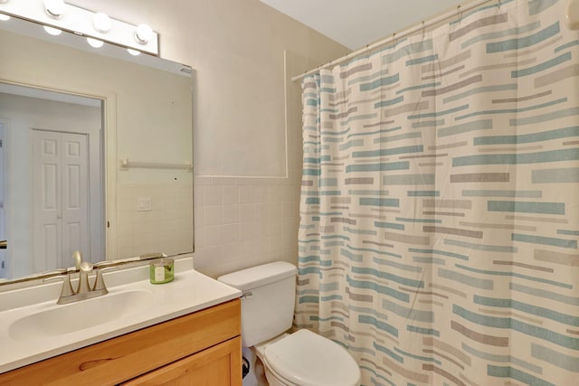 bathroom featuring vanity, toilet, tile walls, and walk in shower