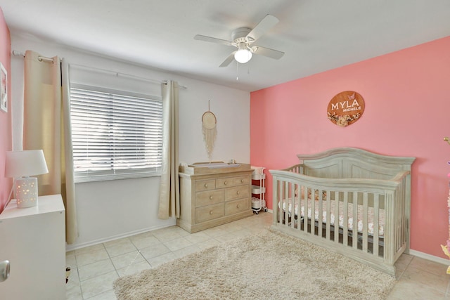 tiled bedroom featuring ceiling fan and a crib