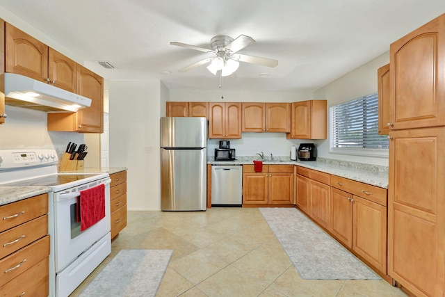 kitchen with light stone countertops, light tile patterned floors, stainless steel appliances, sink, and ceiling fan