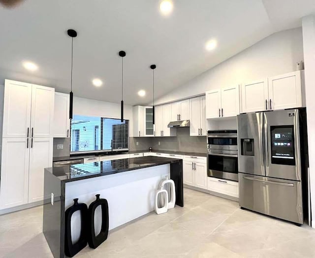 kitchen with appliances with stainless steel finishes, vaulted ceiling, a kitchen island, and white cabinets