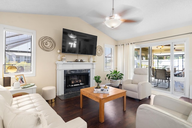 living room with lofted ceiling, a high end fireplace, dark wood-type flooring, and ceiling fan