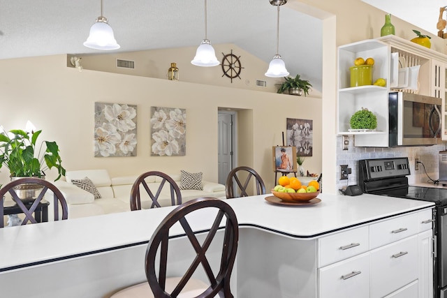 kitchen featuring vaulted ceiling, backsplash, pendant lighting, stainless steel appliances, and white cabinets