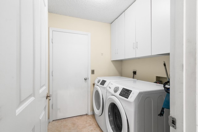 laundry room featuring washer and dryer, cabinets, and a textured ceiling