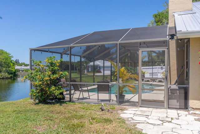 exterior space with a patio, a yard, a water view, and glass enclosure