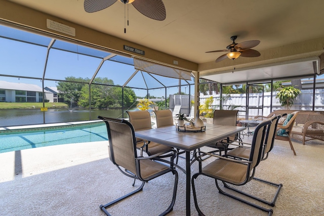 view of pool with ceiling fan, a water view, glass enclosure, and a patio area