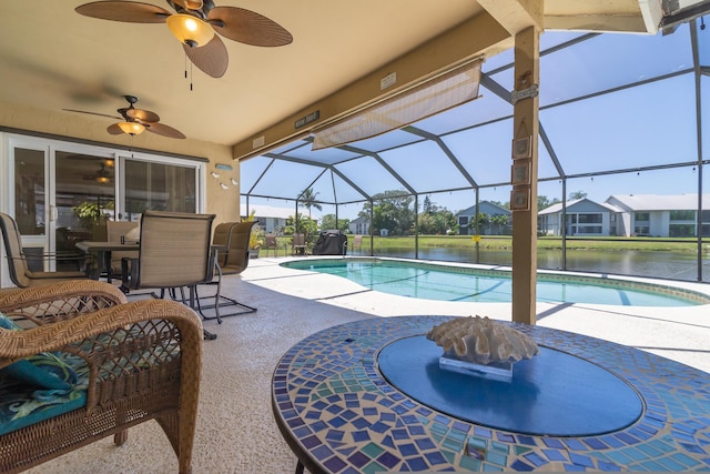 view of pool with a patio, a water view, ceiling fan, and a lanai