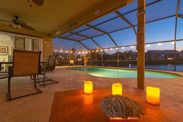 pool at dusk with a patio, ceiling fan, and glass enclosure