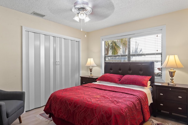 bedroom with light wood-type flooring, a textured ceiling, and ceiling fan