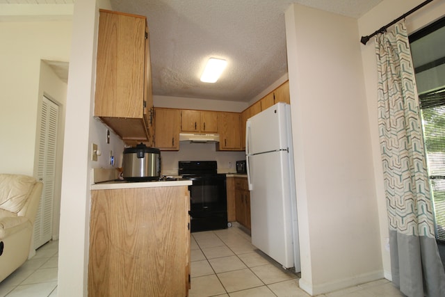 kitchen featuring white fridge, black range, and light tile patterned floors