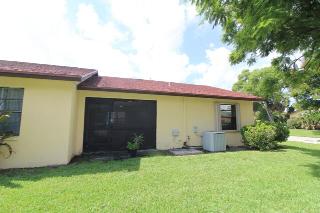 rear view of house featuring a yard and central air condition unit