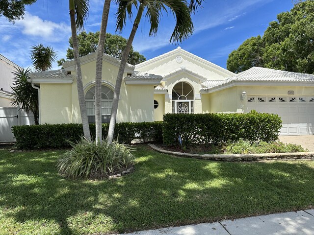 mediterranean / spanish home featuring a garage and a front lawn