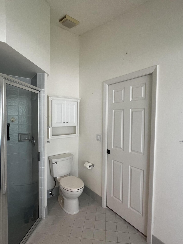 bathroom with a shower with shower door, toilet, and tile patterned floors