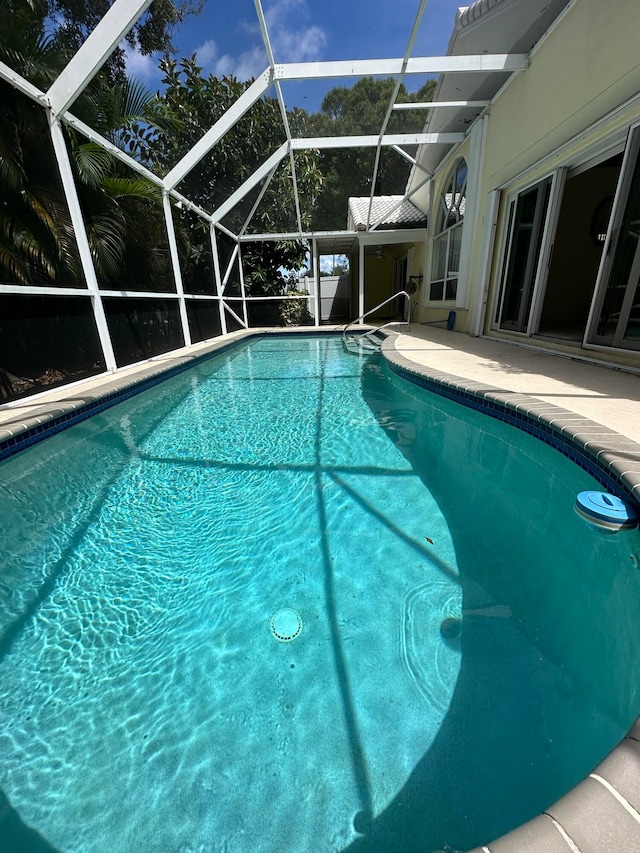 view of swimming pool featuring glass enclosure and a patio area