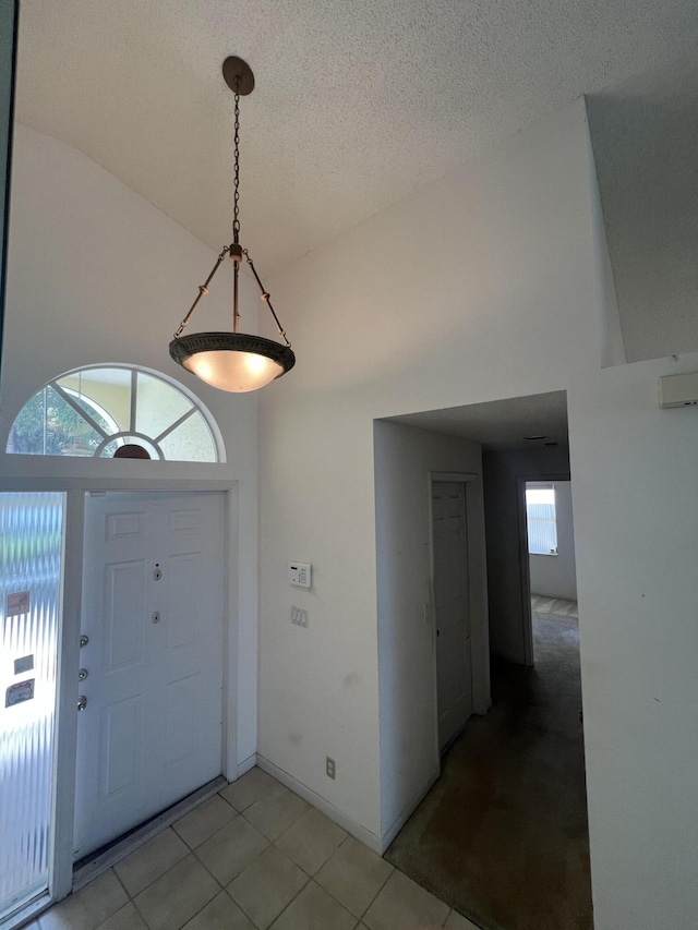 tiled foyer entrance with a textured ceiling and vaulted ceiling