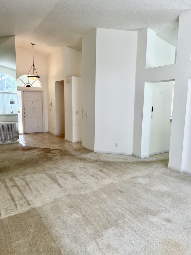 unfurnished living room featuring a textured ceiling, light carpet, high vaulted ceiling, and radiator heating unit