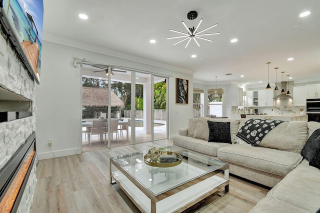 living room featuring light wood-type flooring, a notable chandelier, ornamental molding, and a healthy amount of sunlight