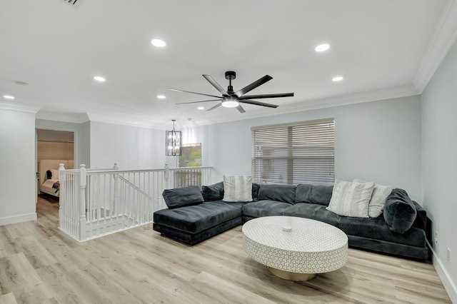 living room with light wood-type flooring, ceiling fan with notable chandelier, and ornamental molding