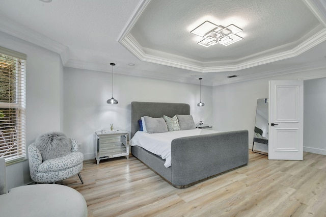 bedroom featuring light hardwood / wood-style floors, a raised ceiling, and crown molding