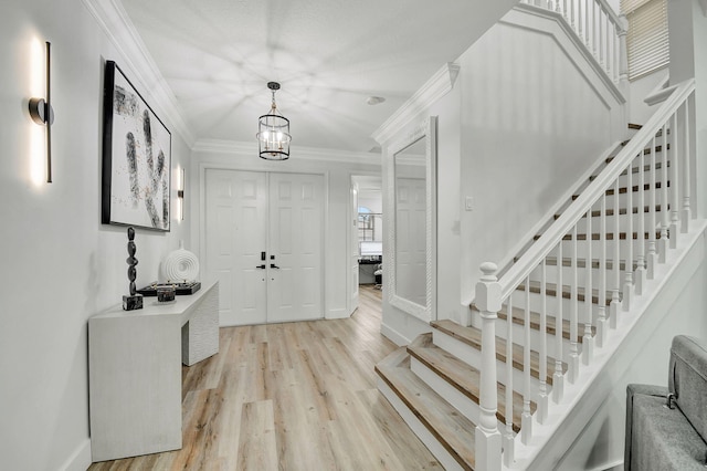 foyer entrance with a notable chandelier, crown molding, and light hardwood / wood-style flooring