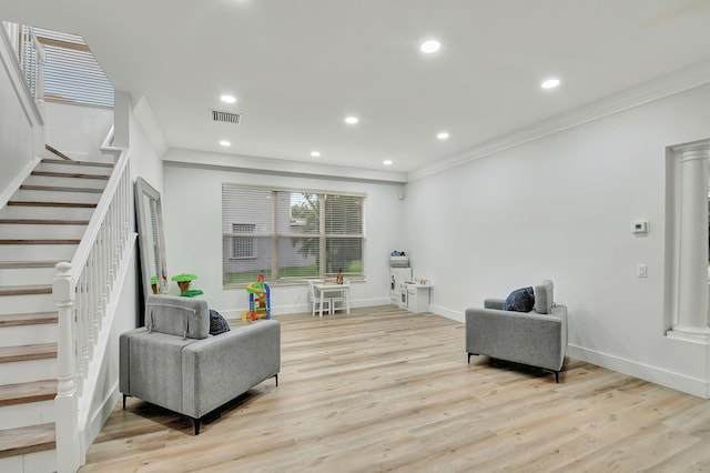 sitting room featuring light hardwood / wood-style floors, ornate columns, and crown molding