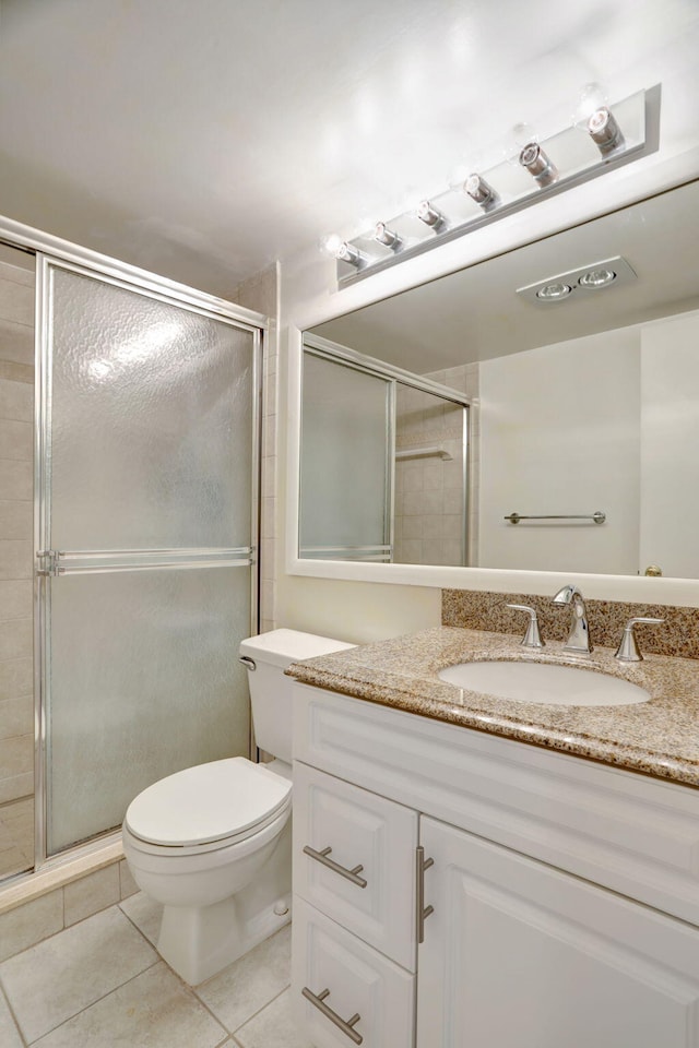 bathroom with tile patterned flooring, vanity, toilet, and a shower with door