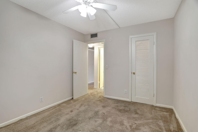 unfurnished bedroom featuring light carpet, a closet, ceiling fan, and a textured ceiling