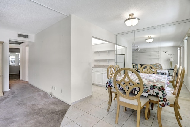 dining room featuring a textured ceiling and light colored carpet