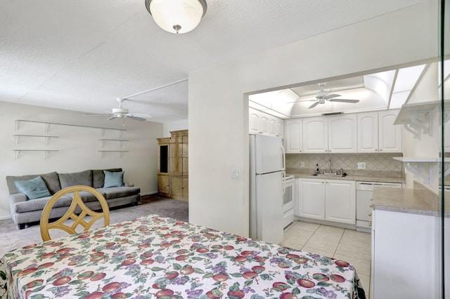 interior space with light tile patterned flooring, white fridge, a textured ceiling, ceiling fan, and sink