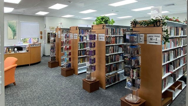 interior space with a drop ceiling and carpet flooring