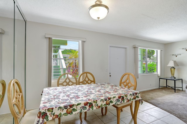 dining area with a textured ceiling and light carpet