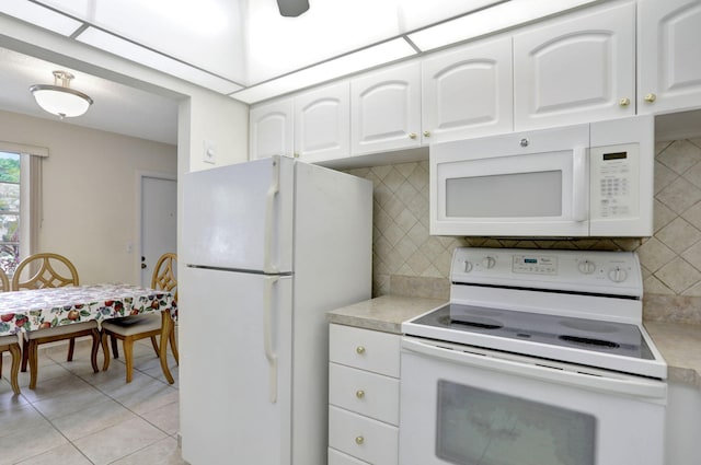 kitchen with white appliances, white cabinetry, light tile patterned floors, and backsplash