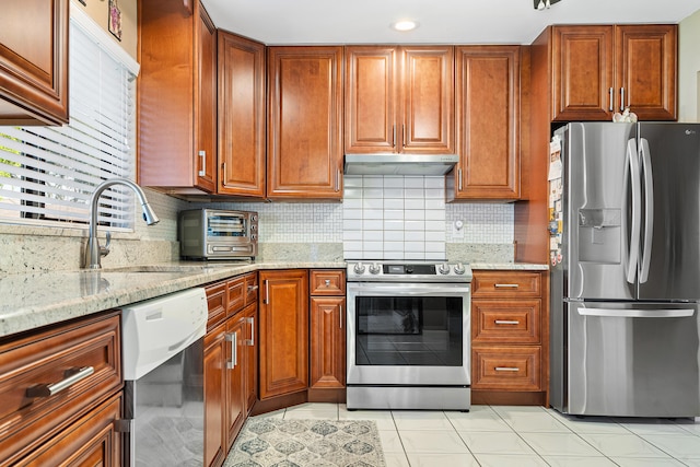 kitchen featuring decorative backsplash, a wealth of natural light, light stone counters, and appliances with stainless steel finishes