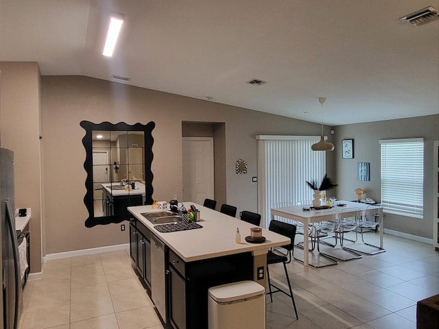 kitchen with a kitchen bar, lofted ceiling, hanging light fixtures, sink, and a kitchen island with sink