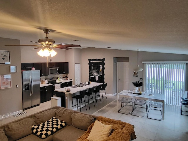 living room with lofted ceiling, a textured ceiling, and ceiling fan