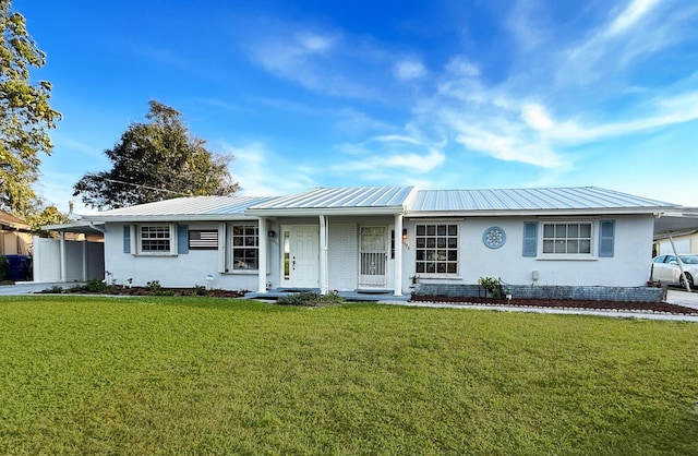 ranch-style house with a carport, metal roof, a front yard, and stucco siding