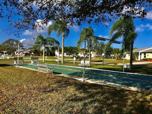 view of home's community with shuffleboard and a lawn