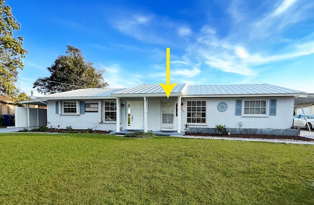 single story home featuring metal roof, stucco siding, and a front lawn