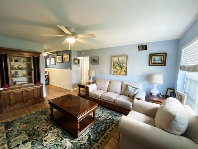 living area with visible vents, baseboards, a ceiling fan, and wood finished floors