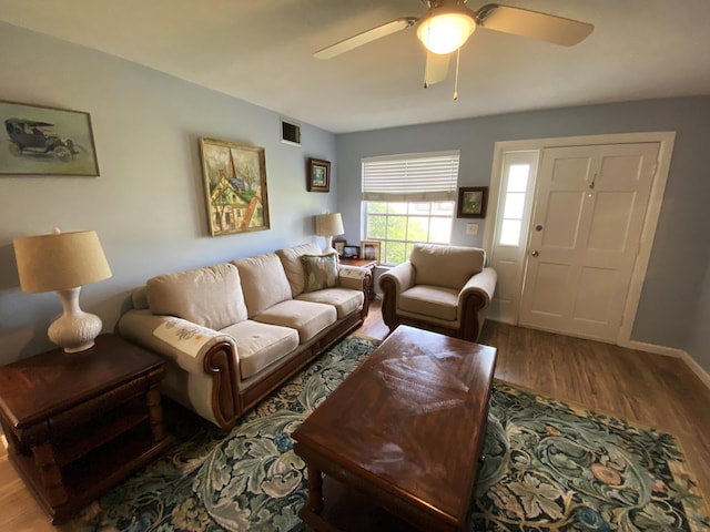living area with visible vents, baseboards, a ceiling fan, and wood finished floors